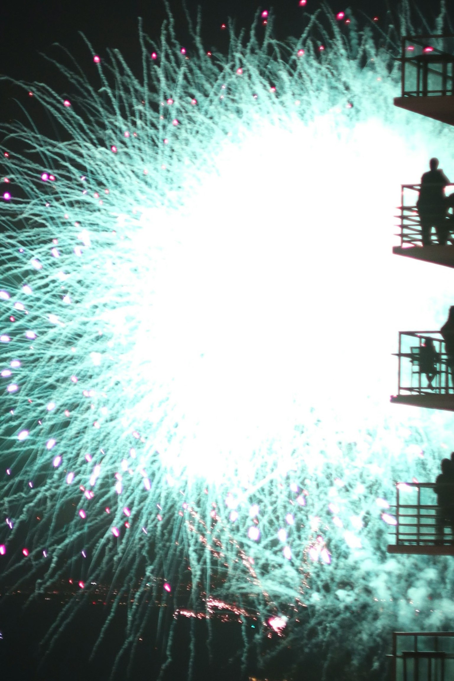 夜空に広がる青い花火とシルエットの人々