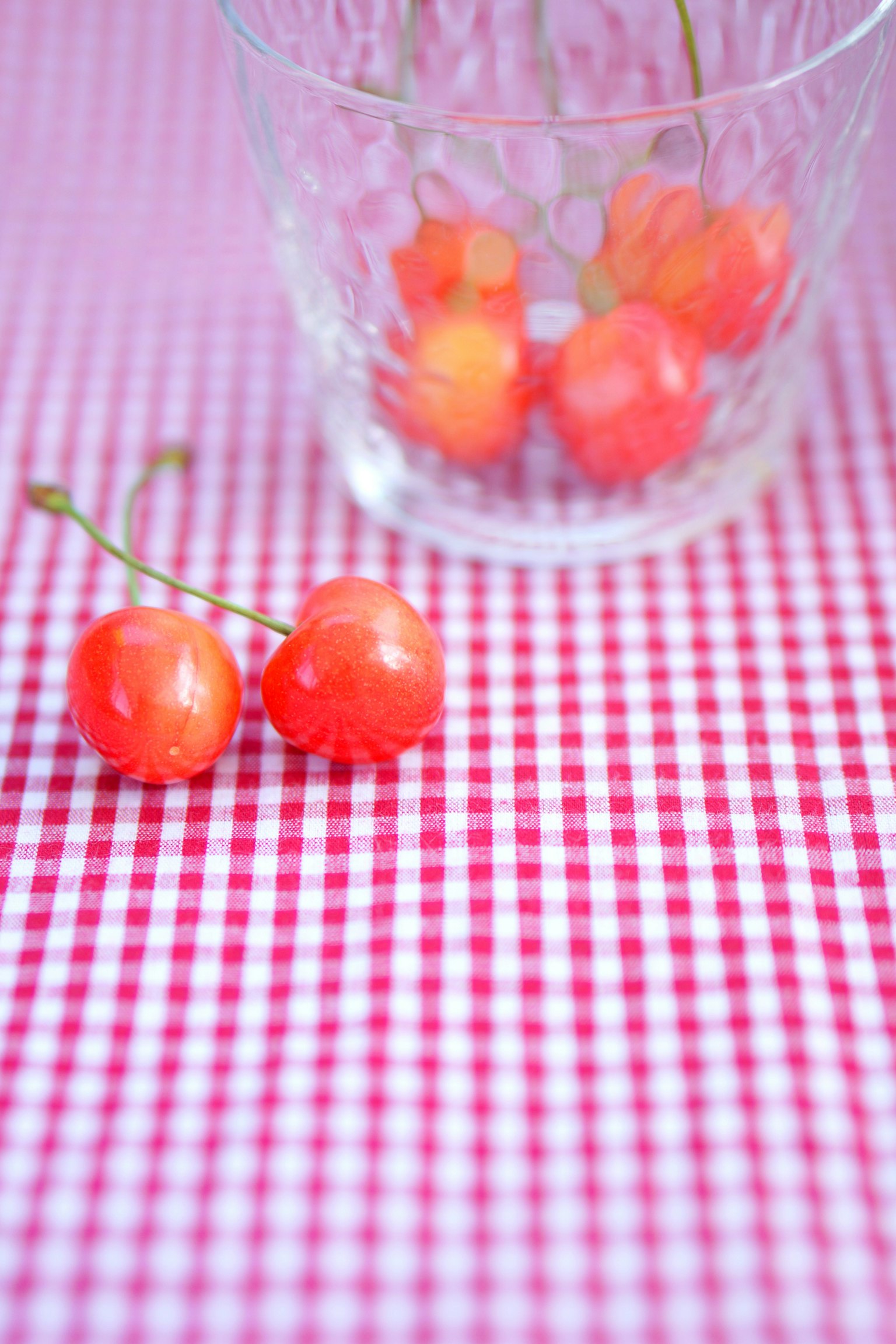 Cerises rouges dans un verre transparent sur une nappe à carreaux
