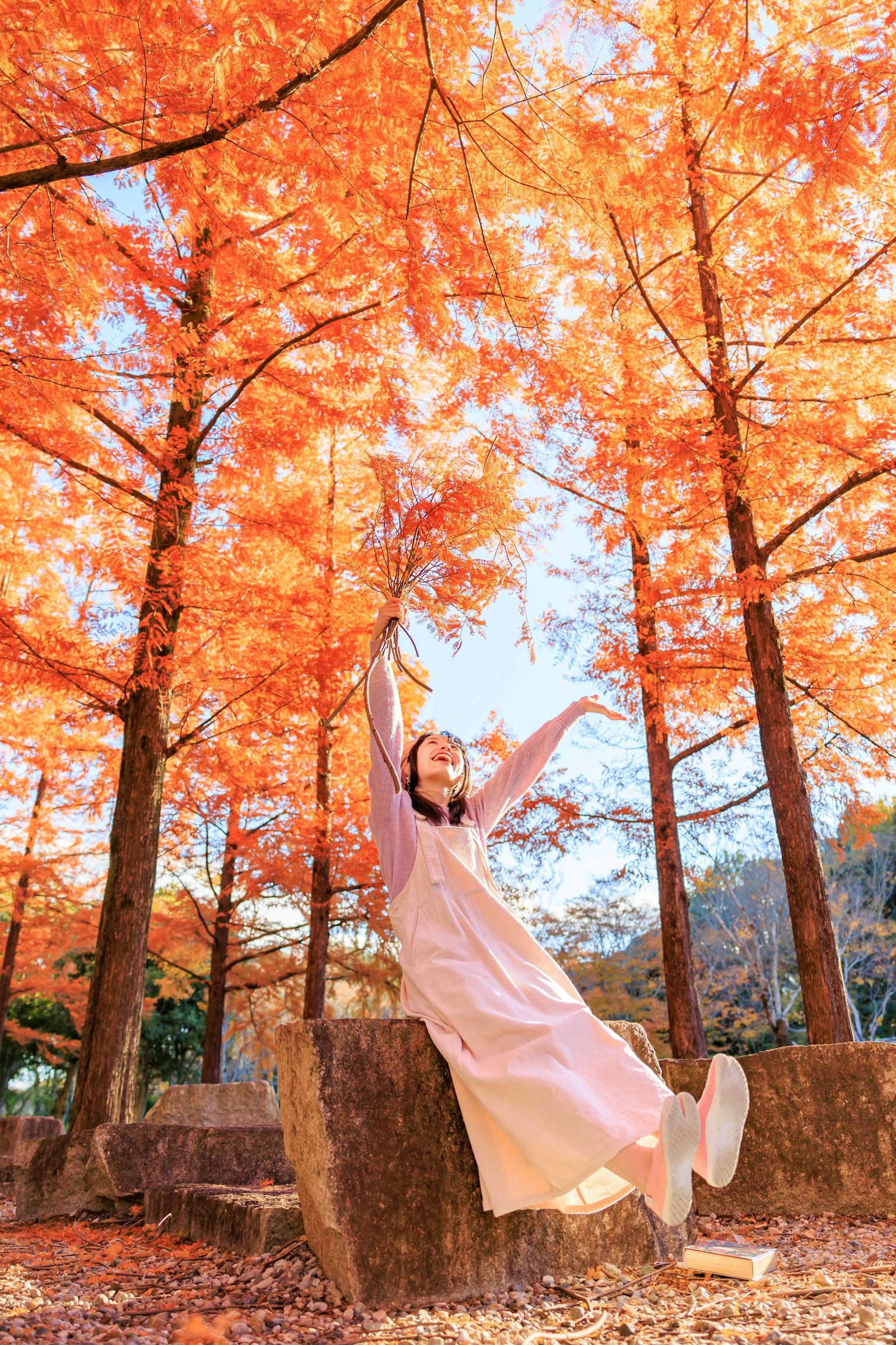 Femme posant au milieu de feuilles d'automne vibrantes