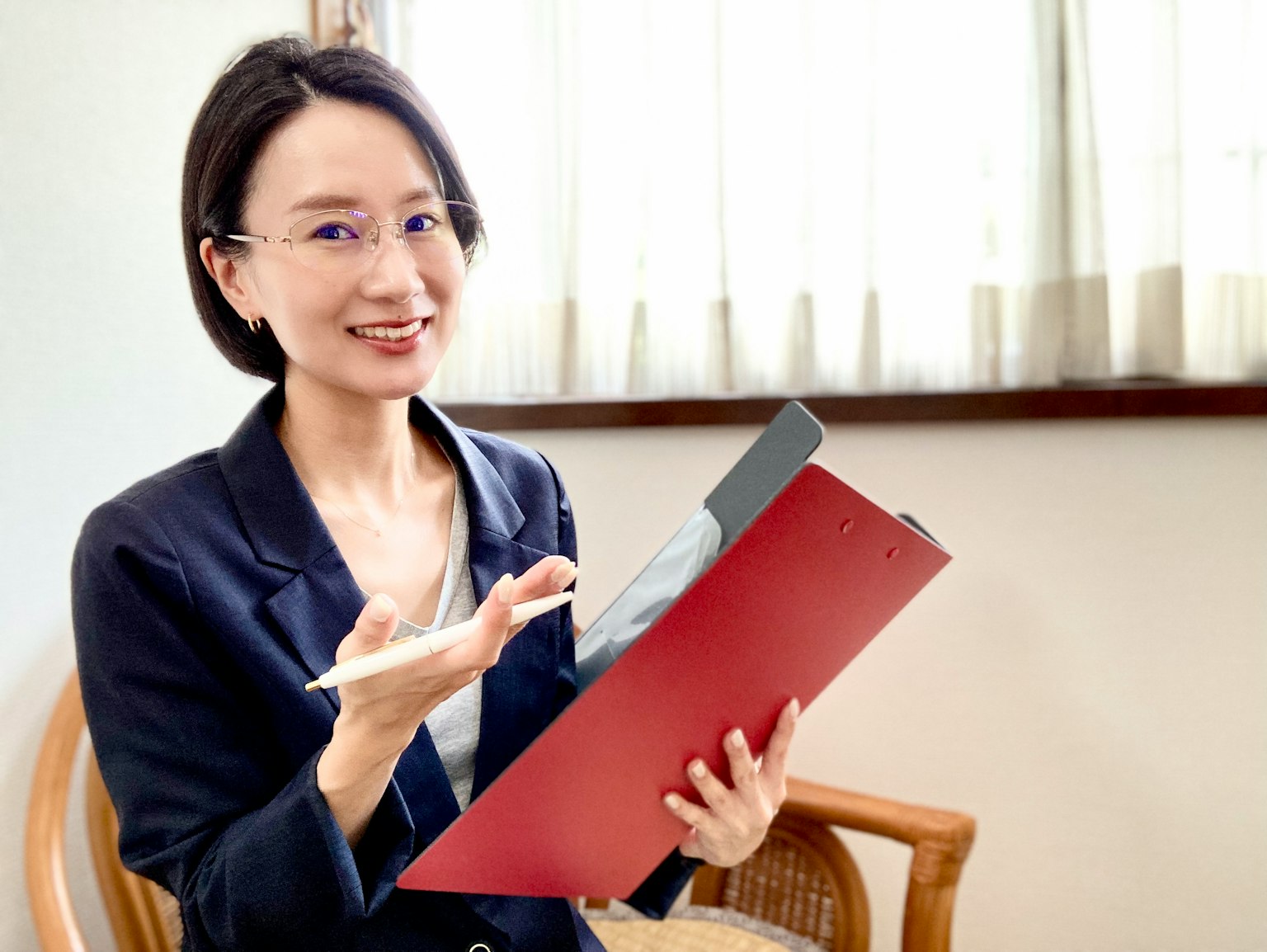 Femme jeune souriante tenant un dossier rouge