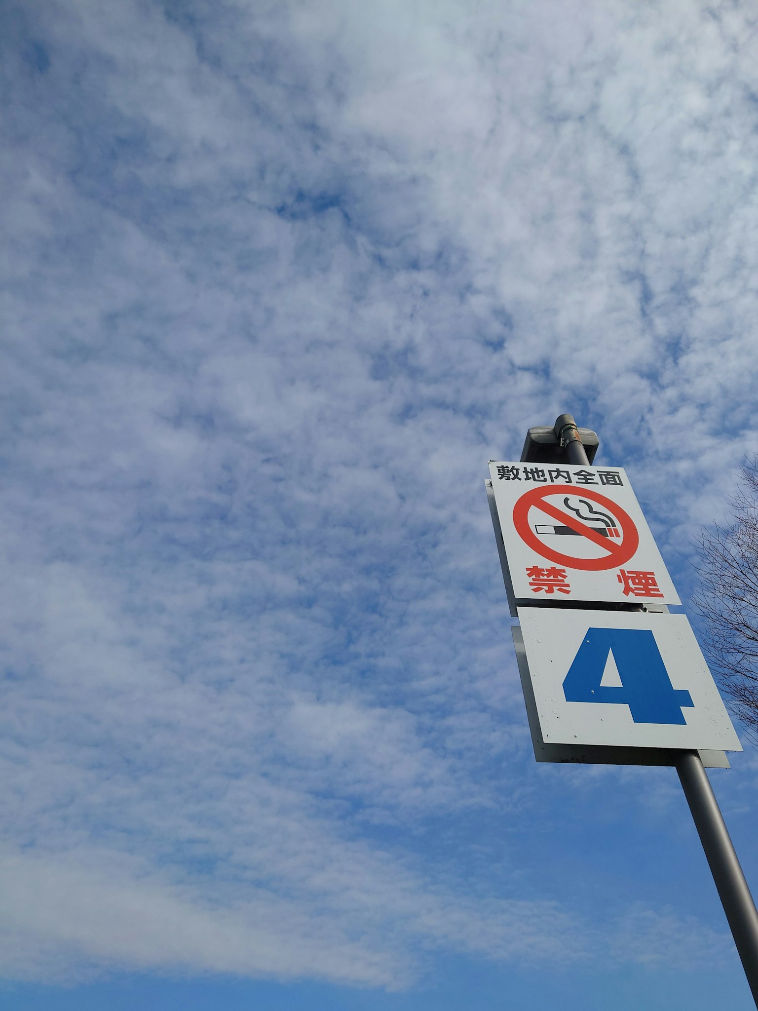 Schild mit Nichtraucherzeichen und Nummer 4 unter einem blauen Himmel