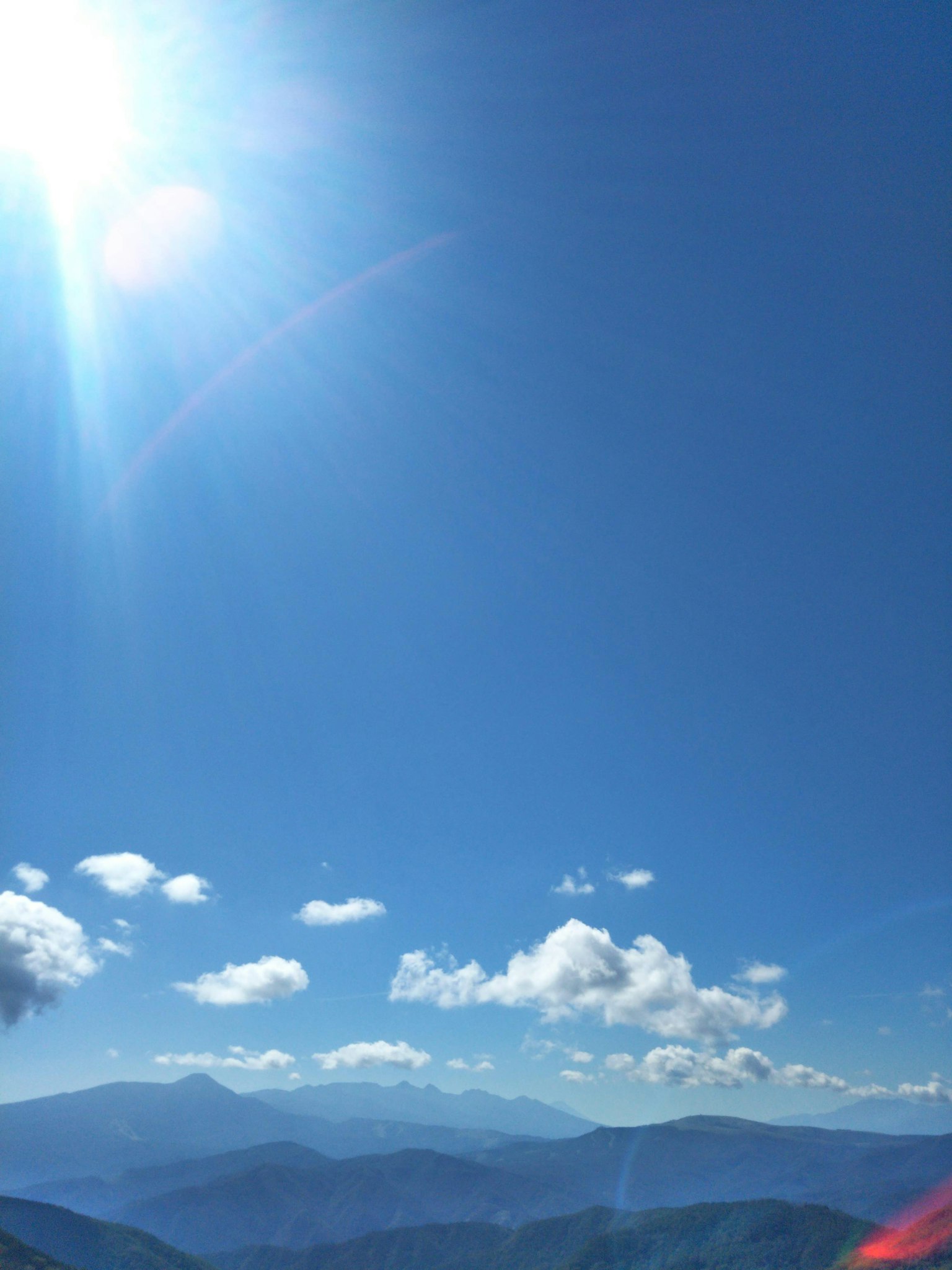 Bright blue sky with white clouds over mountain landscape