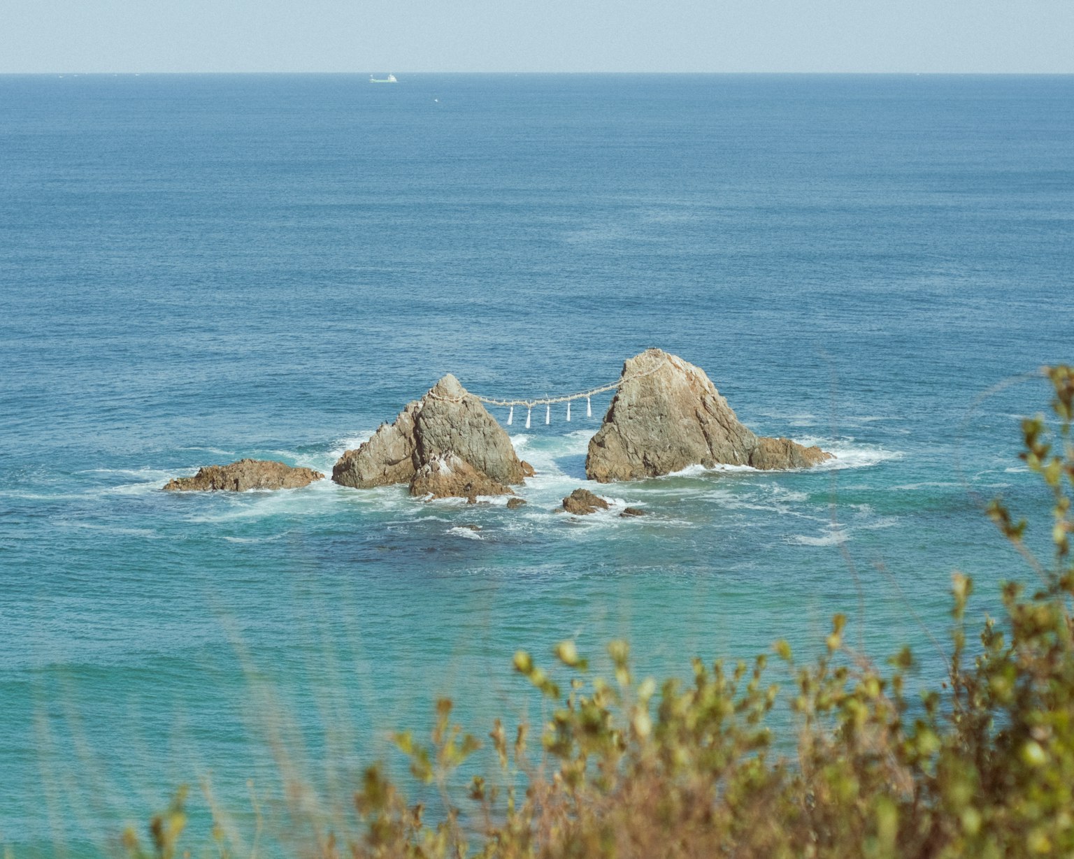 Photo d'un océan bleu avec deux rochers reliés par un pont