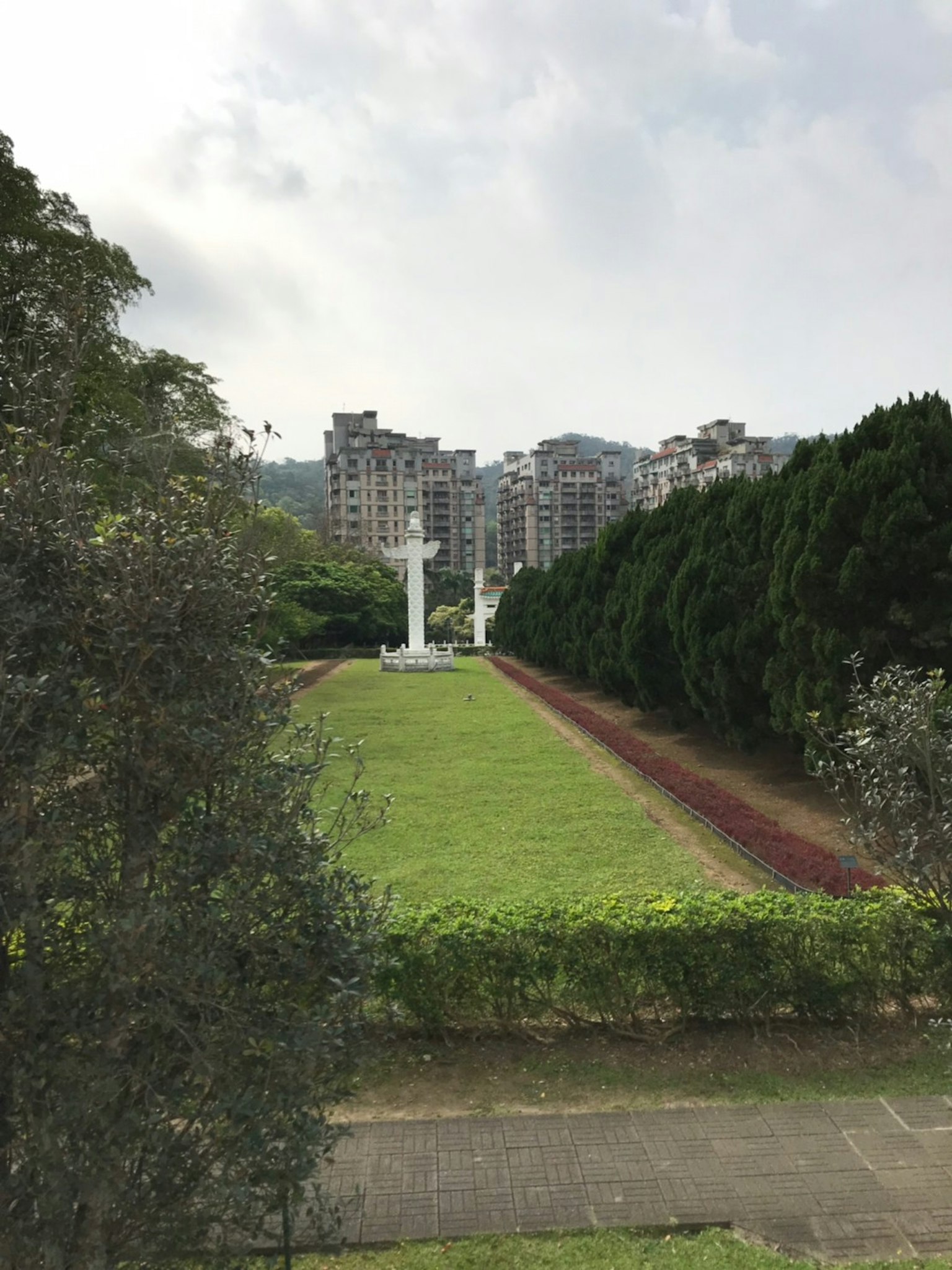 Vista del parque con columnas blancas rodeadas de árboles verdes y edificios altos