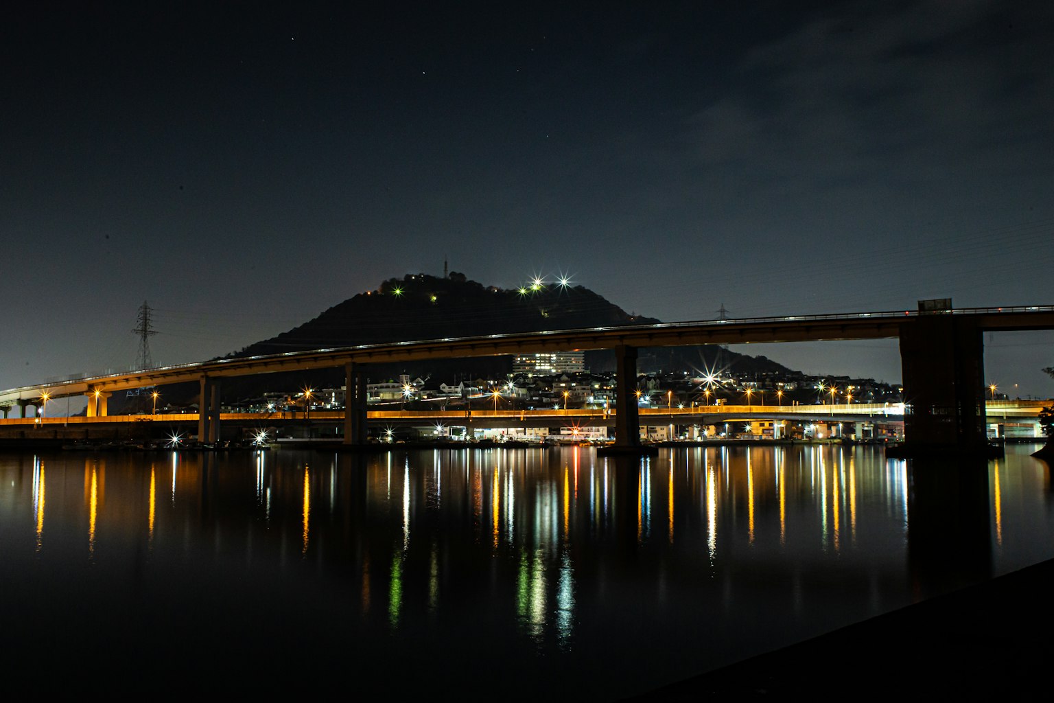 Pemandangan malam jembatan dan gunung yang terpantul di air tenang