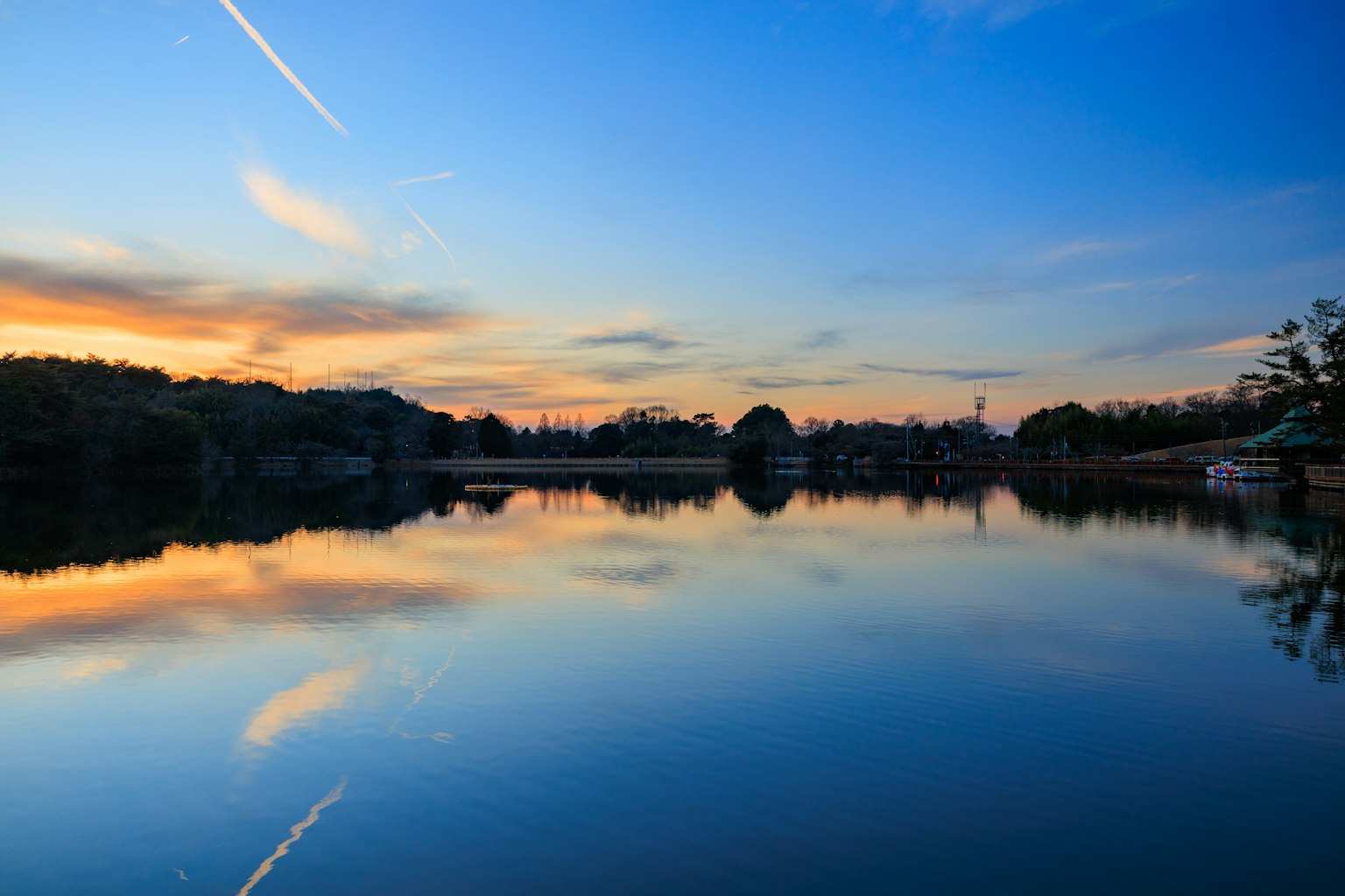 Serene lake view with vibrant sunset reflections and clear blue sky