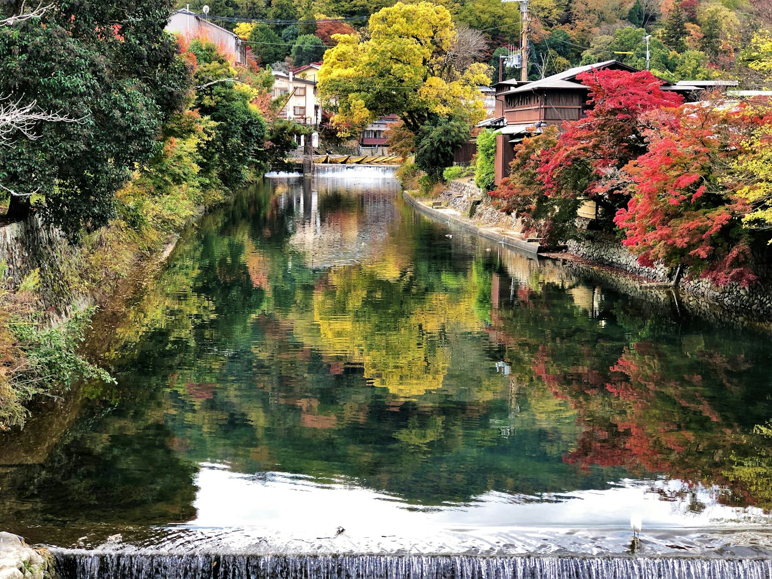 Paisaje de río sereno que refleja un follaje otoñal vibrante