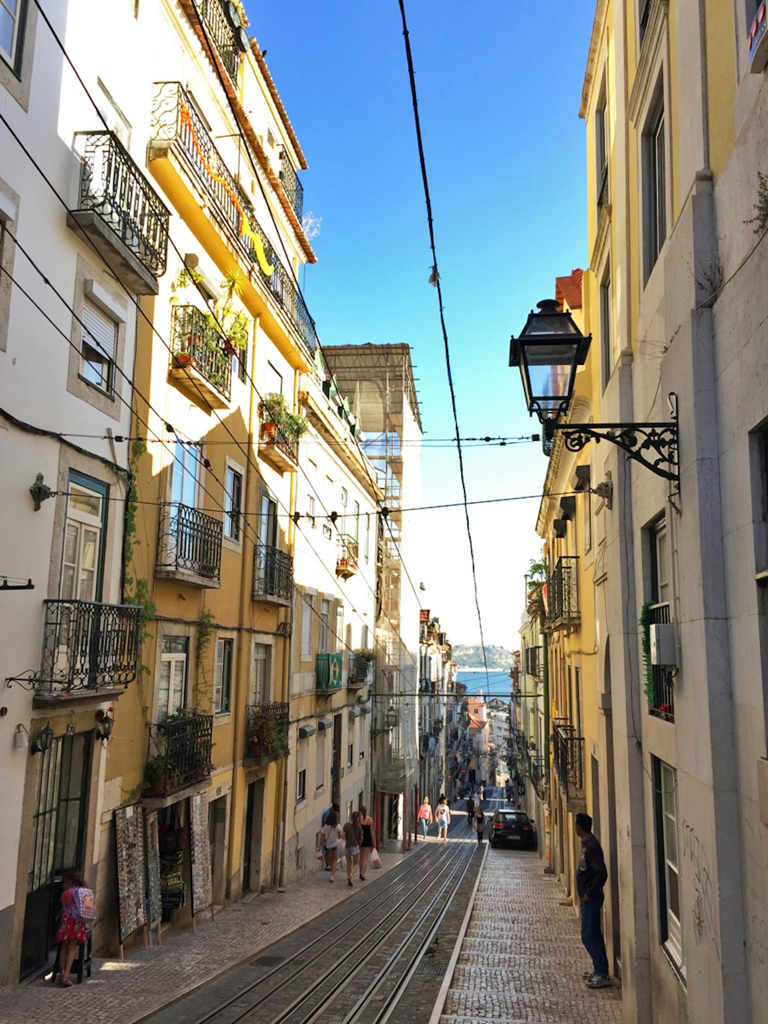 Narrow street in Lisbon with colorful buildings and clear blue sky