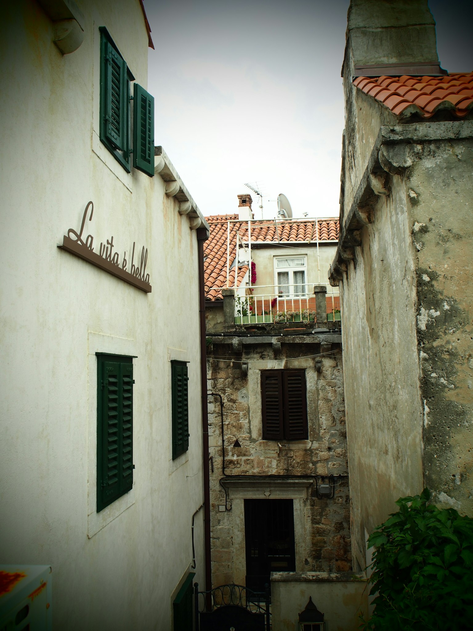 Callejón estrecho entre viejos edificios de piedra con persianas verdes