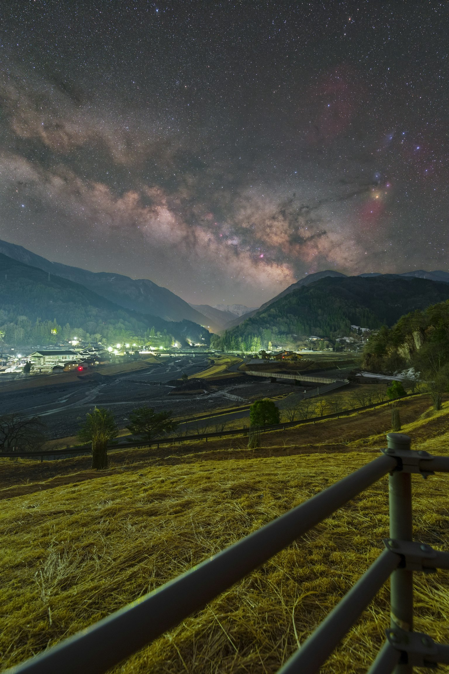 Vue nocturne d'un village paisible avec montagnes et ciel étoilé