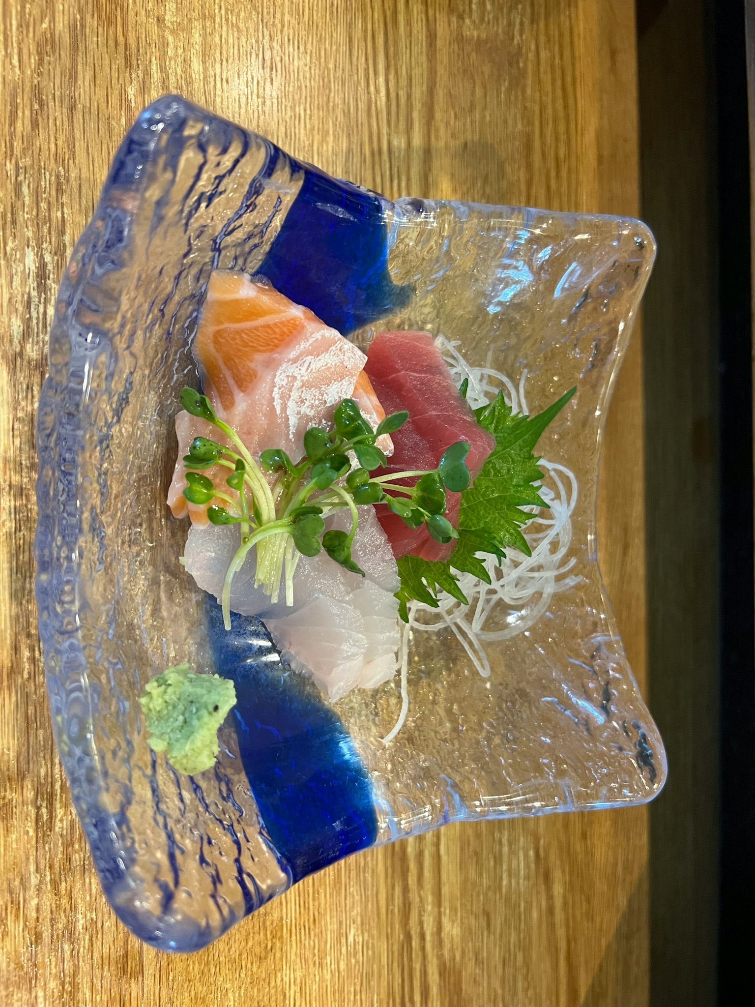 Sashimi berwarna-warni disajikan di atas piring kaca yang indah
