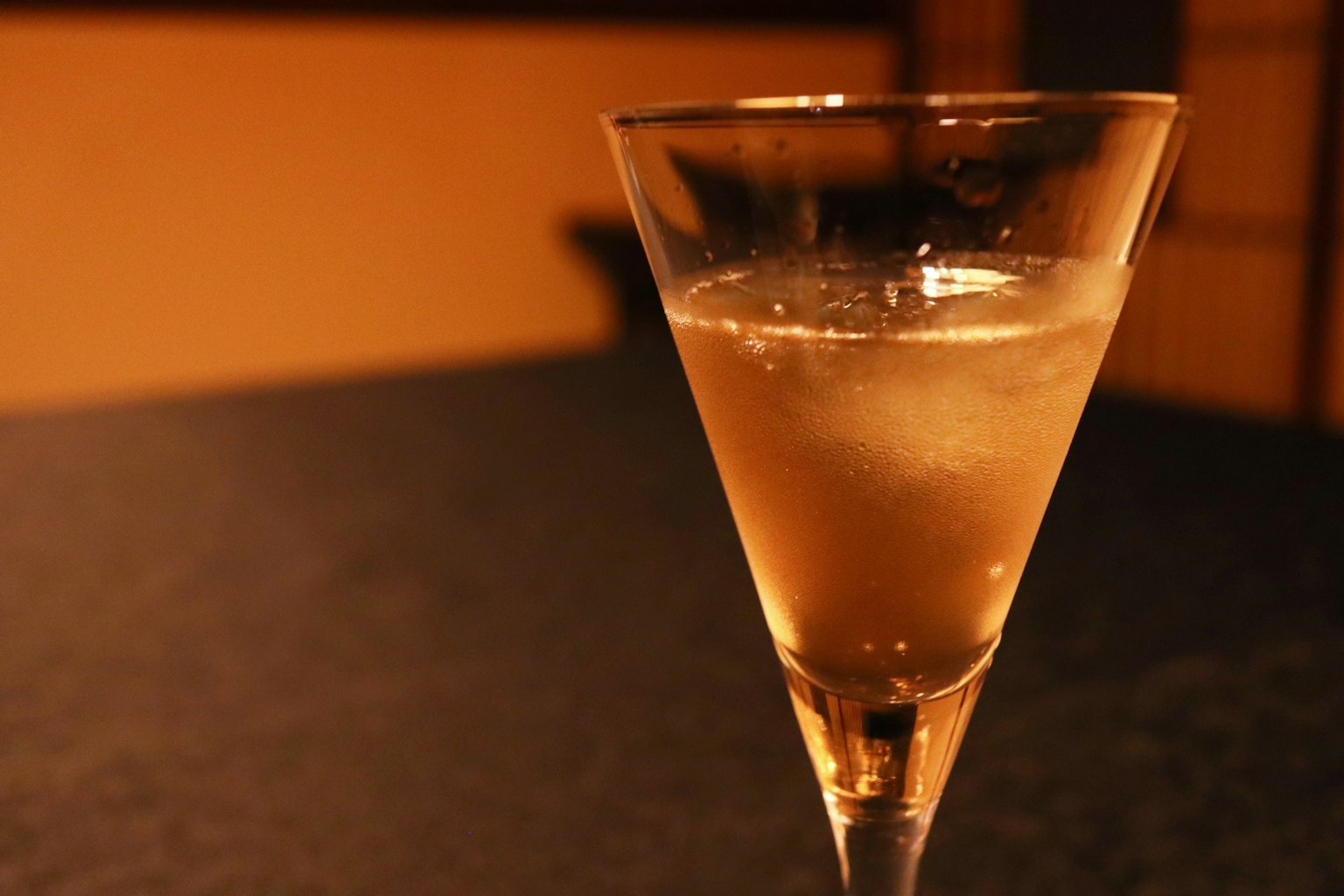Un bicchiere da cocktail trasparente pieno di una bevanda dorata chiara