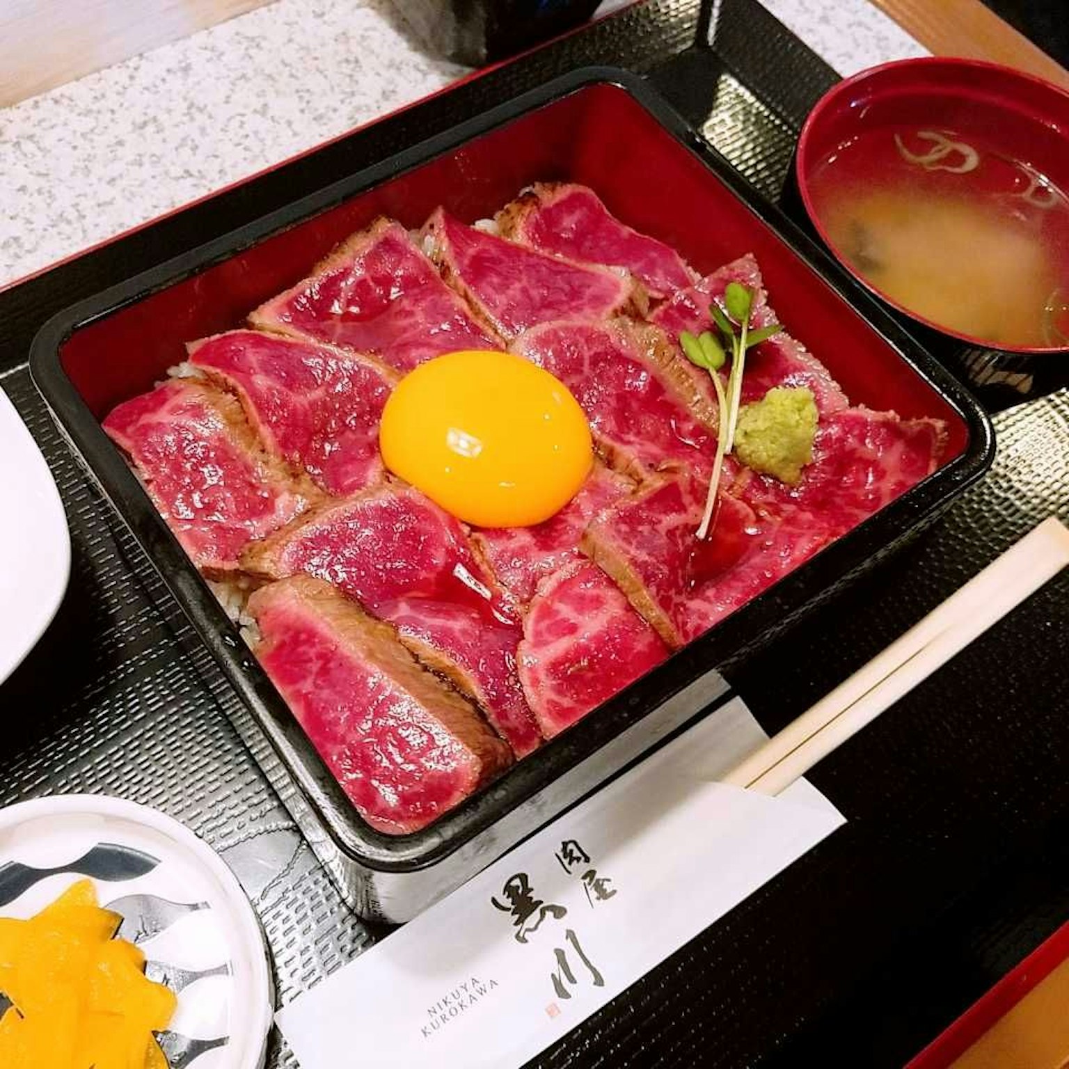 เนื้อวากิวสไลซ์พร้อมไข่ดิบและวาซาบิในกล่องแบบดั้งเดิม