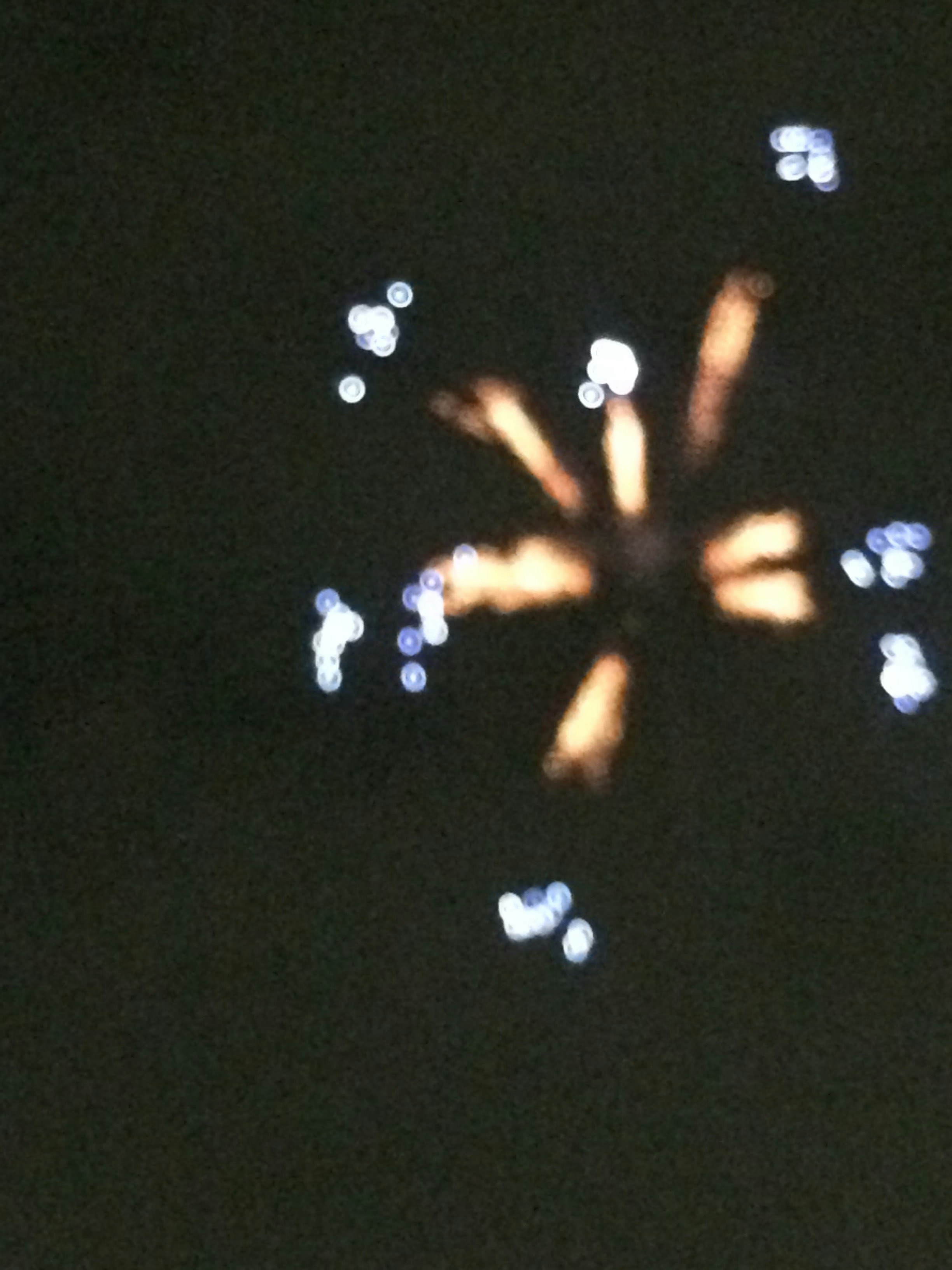夜空に浮かぶ光の点と放射状の光