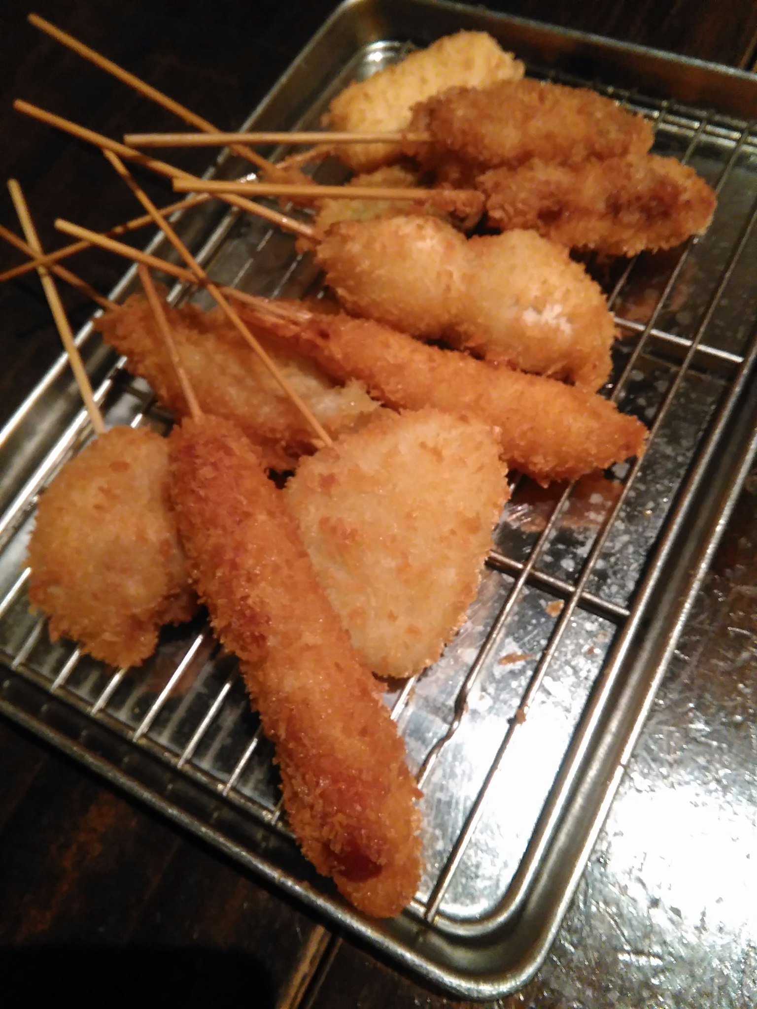 Una variedad de brochetas fritas en una bandeja de metal