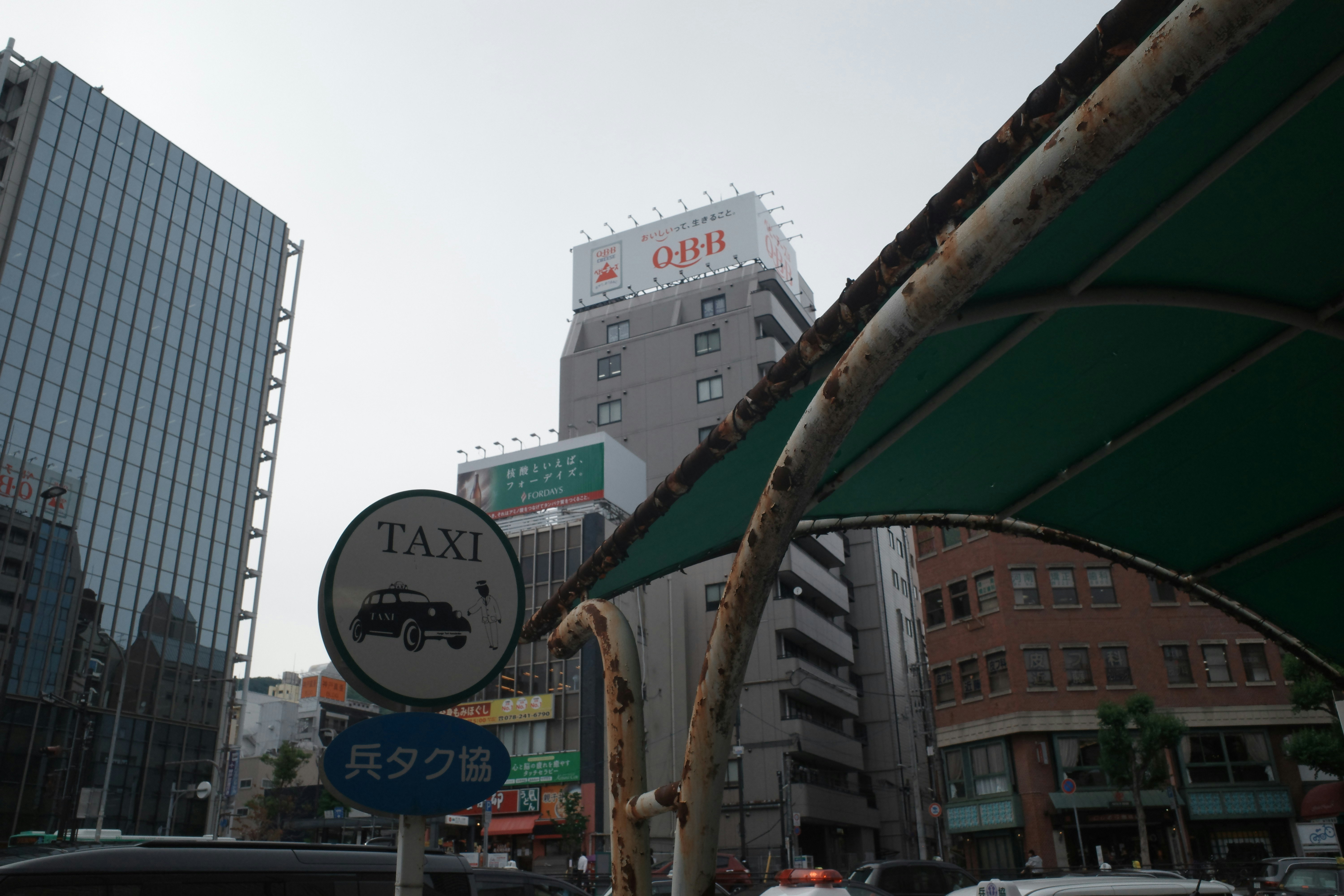 「TAXI」看板とビル群が並ぶ都市の交差点の風景