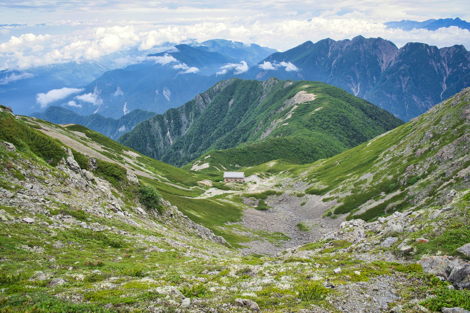 一座小建築被綠色山脈和山谷環繞