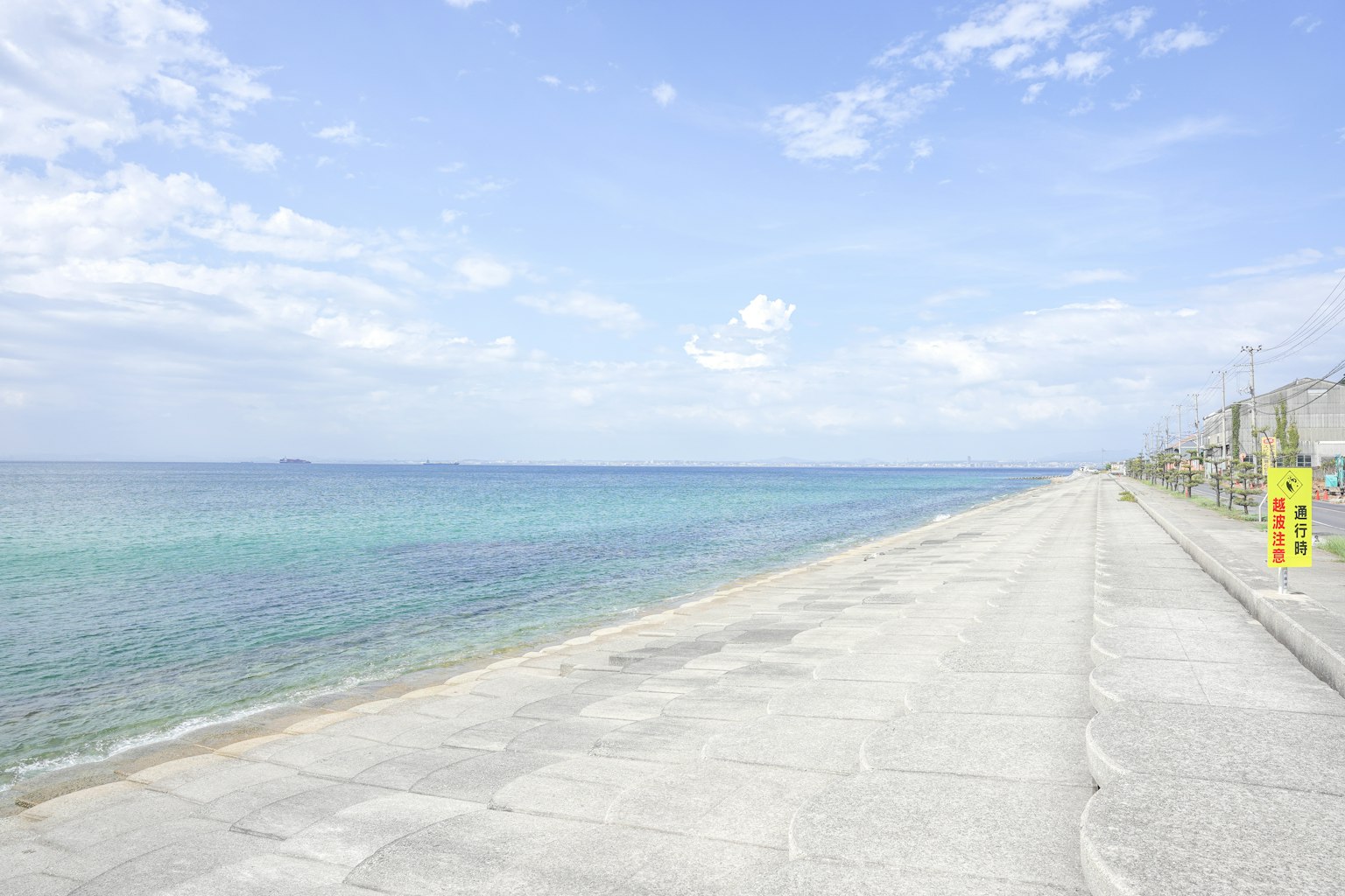 Vista de playa escénica con mar y cielo azules a lo largo de un paseo de concreto