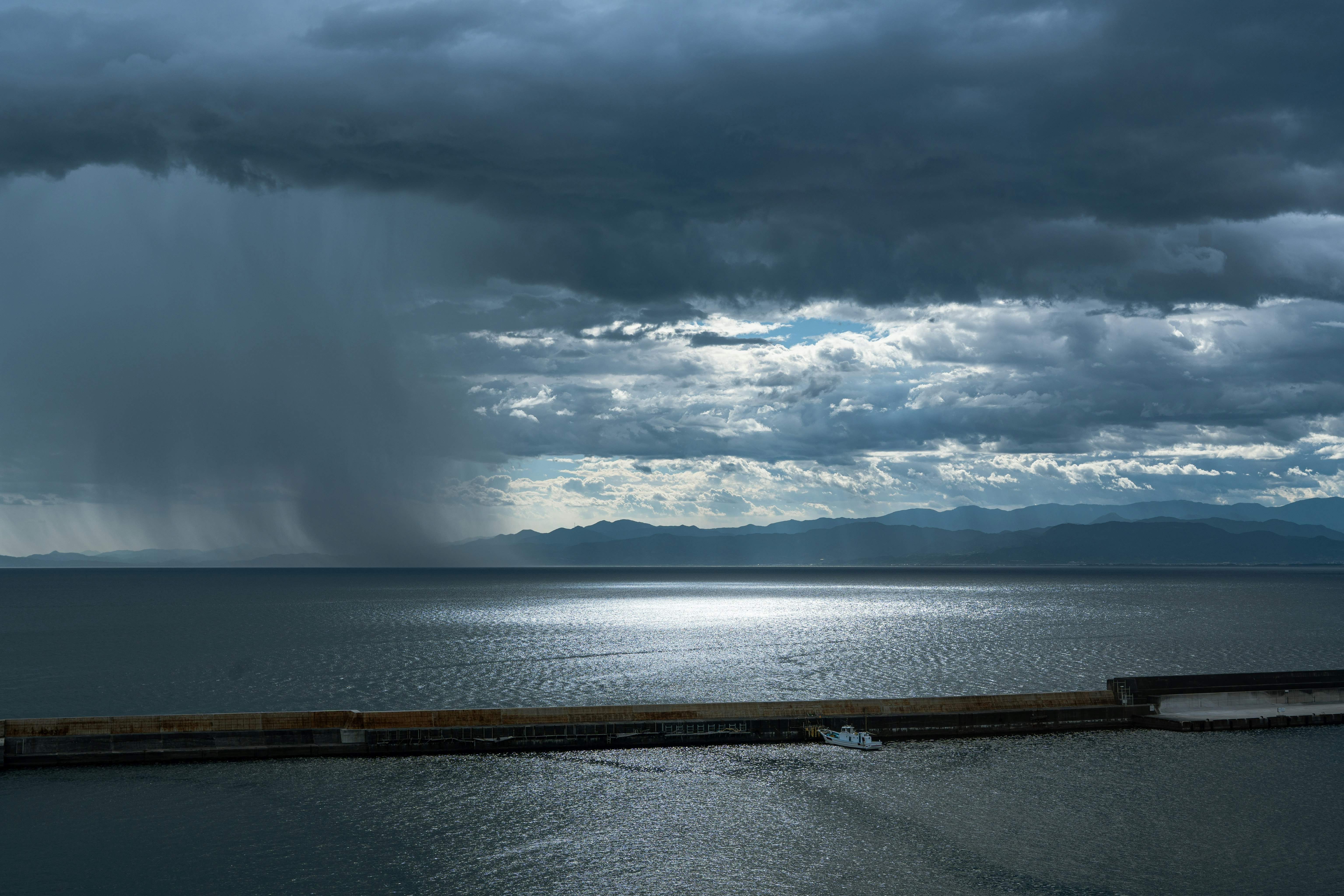 雨雲の下に広がる湖と水平線の風景