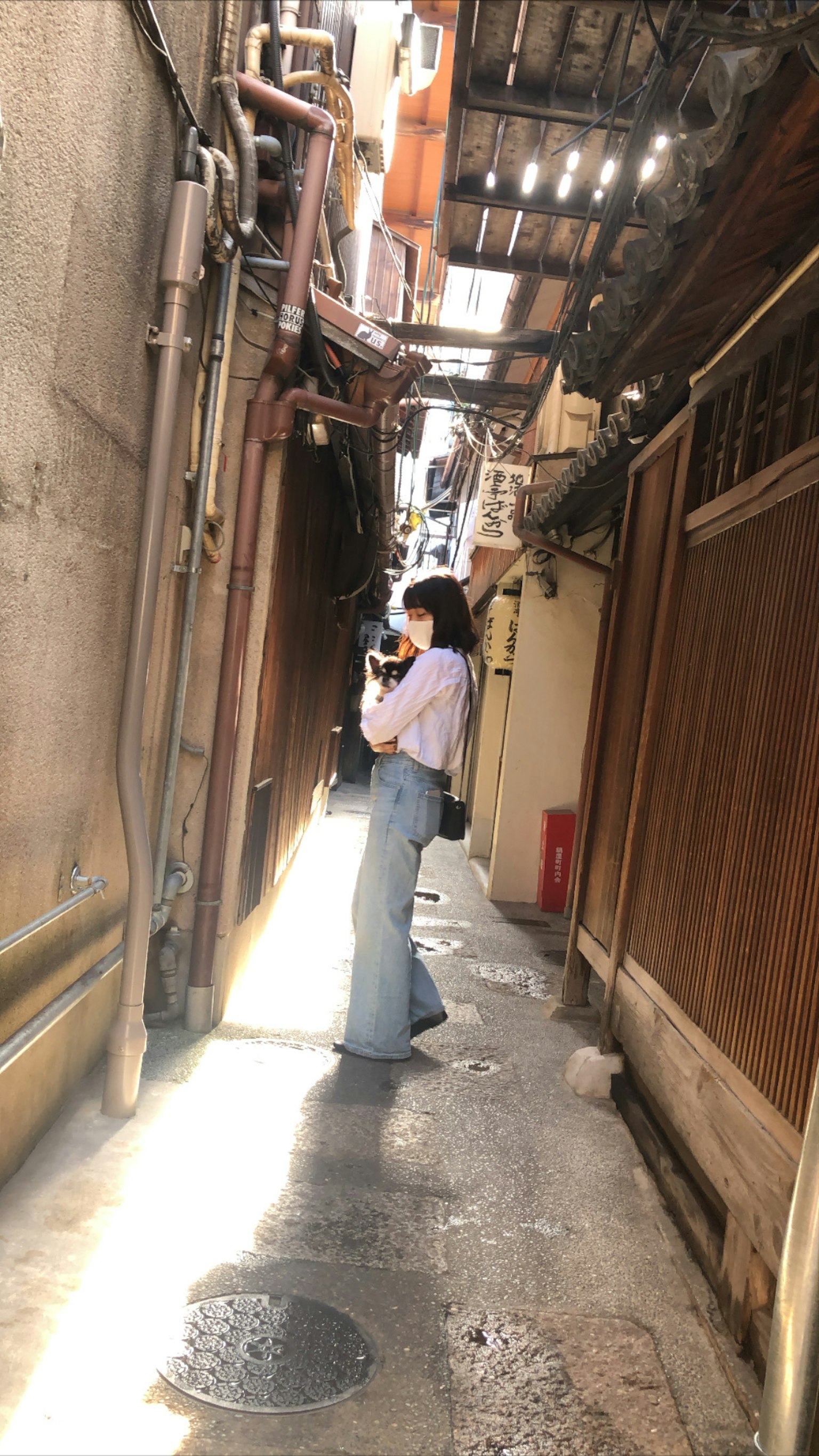 나무 벽이 있는 좁은 골목에 서 있는 여성