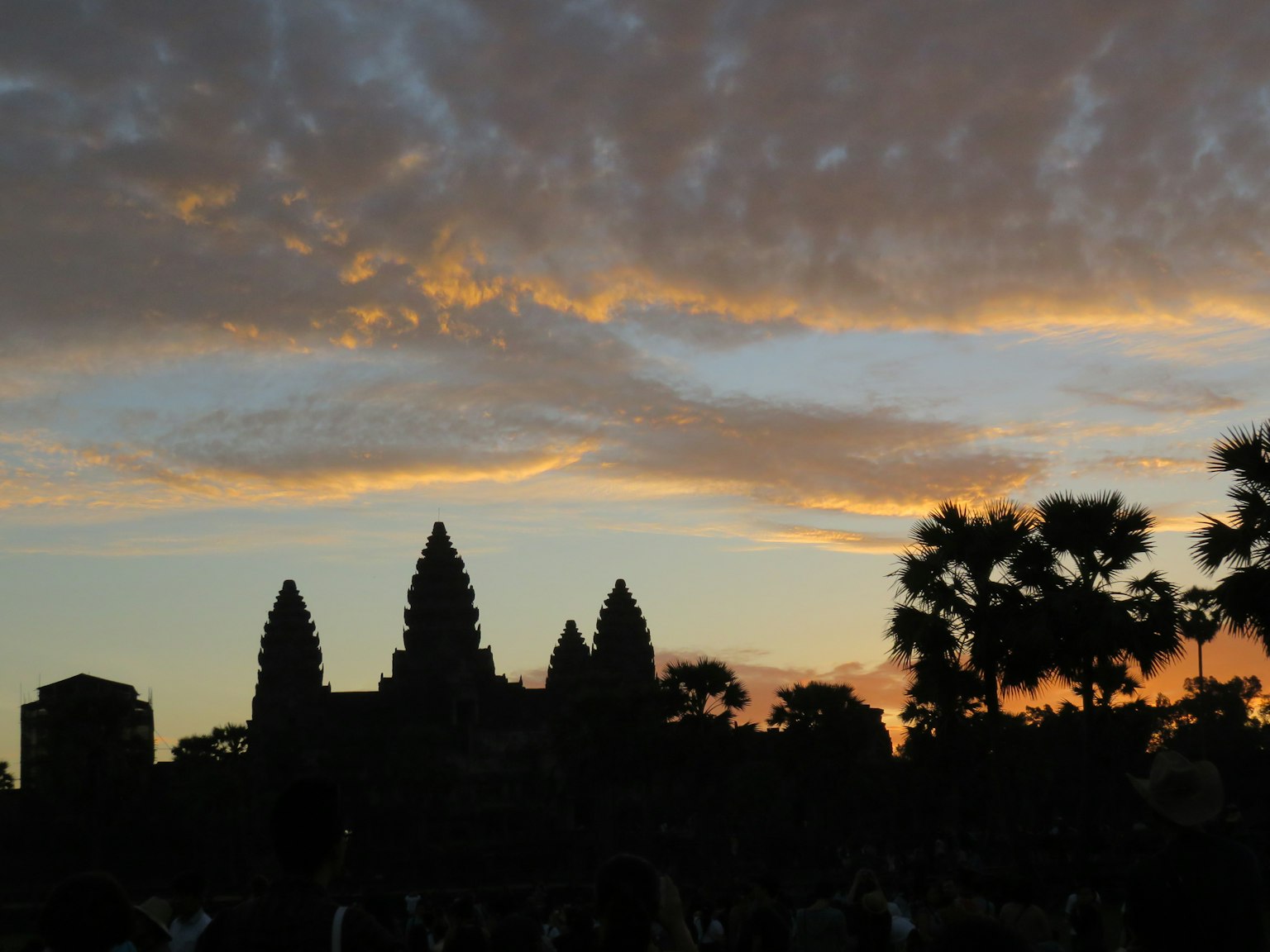 Siluet Angkor Wat melawan langit senja dengan pohon palem