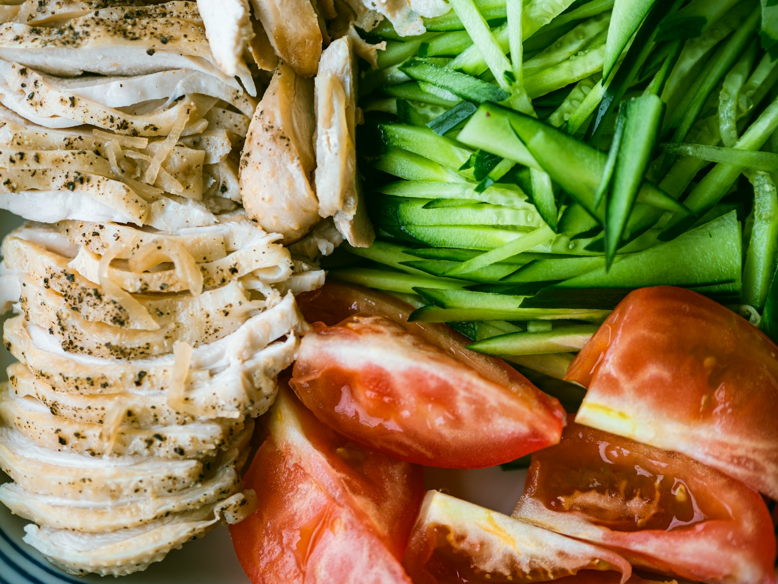 Dada ayam yang diiris dengan tomat dan daun bawang iris halus di piring