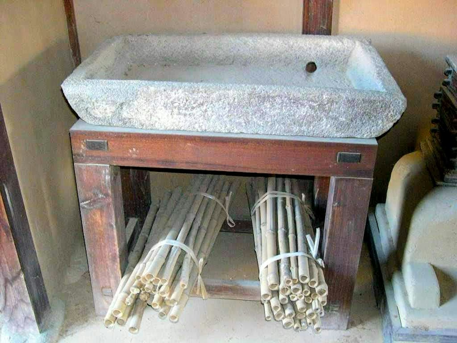 Bồn đá trên giá gỗ với bó tre