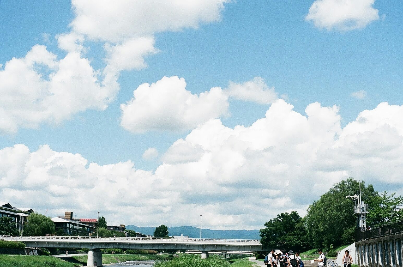 vue d’une promenade au bord de la rivière et d’un pont sous des nuages cumulonimbus