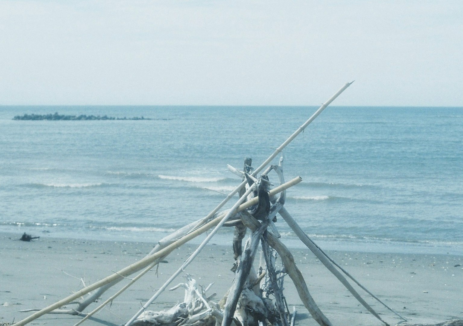 Struttura di legno alla deriva sulla spiaggia con sfondo marino calmo