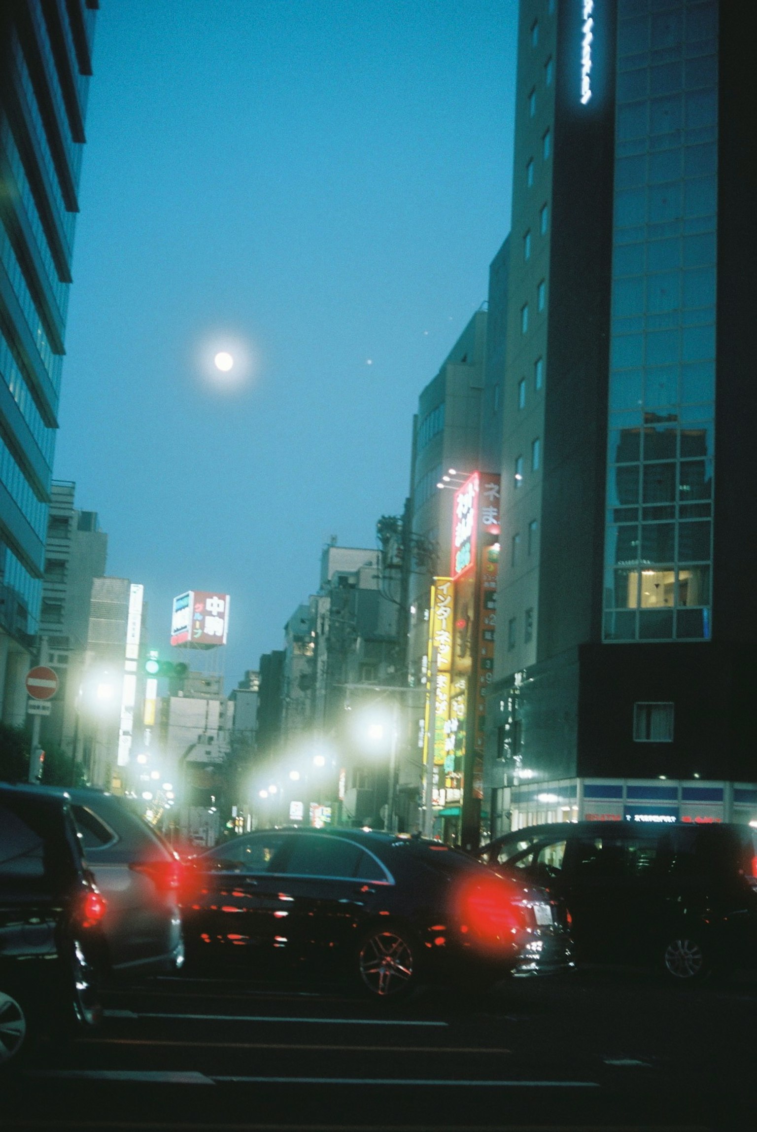 Night cityscape featuring a bright moon and illuminated signs