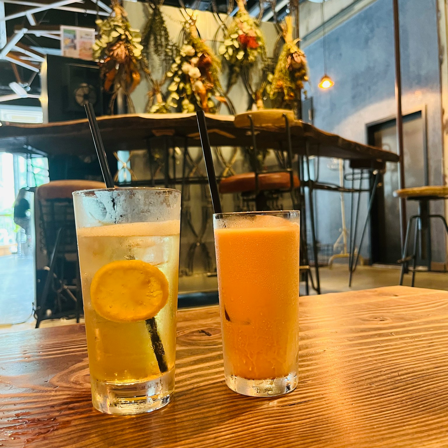 Deux boissons sur une table en bois l'une avec du citron et l'autre orange dans un café élégant