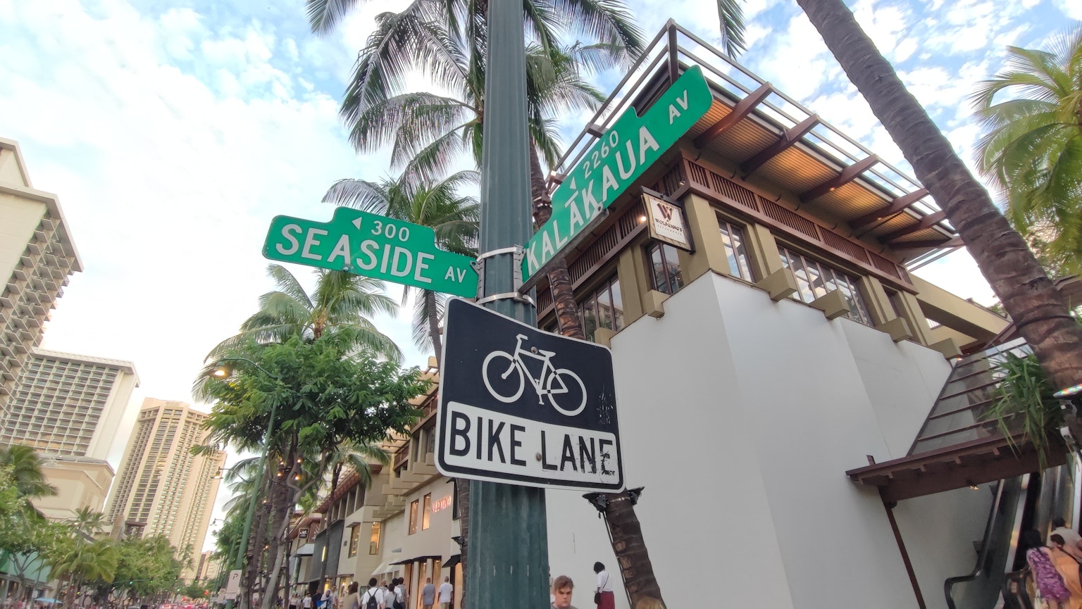 ป้ายถนนสำหรับ Seaside และ Kalakaua พร้อมป้ายเลนจักรยานในบรรยากาศเขตร้อน