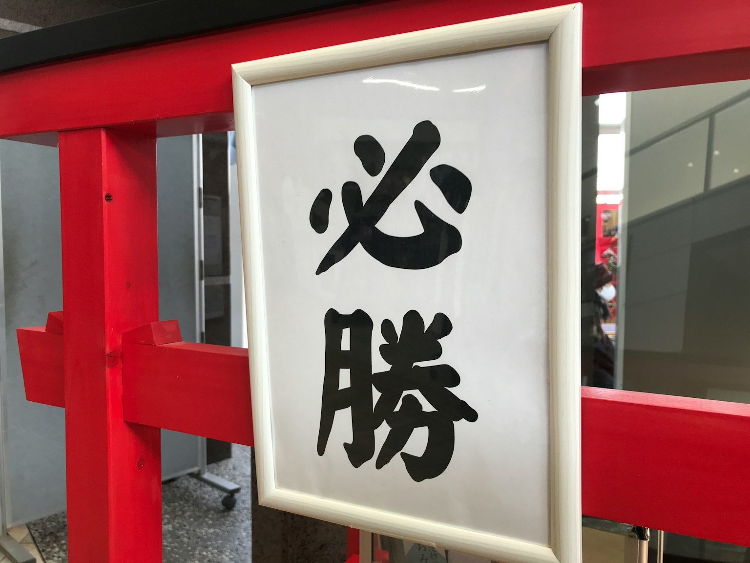 靠近红色鸟居的白色标志上写有汉字'必胜'