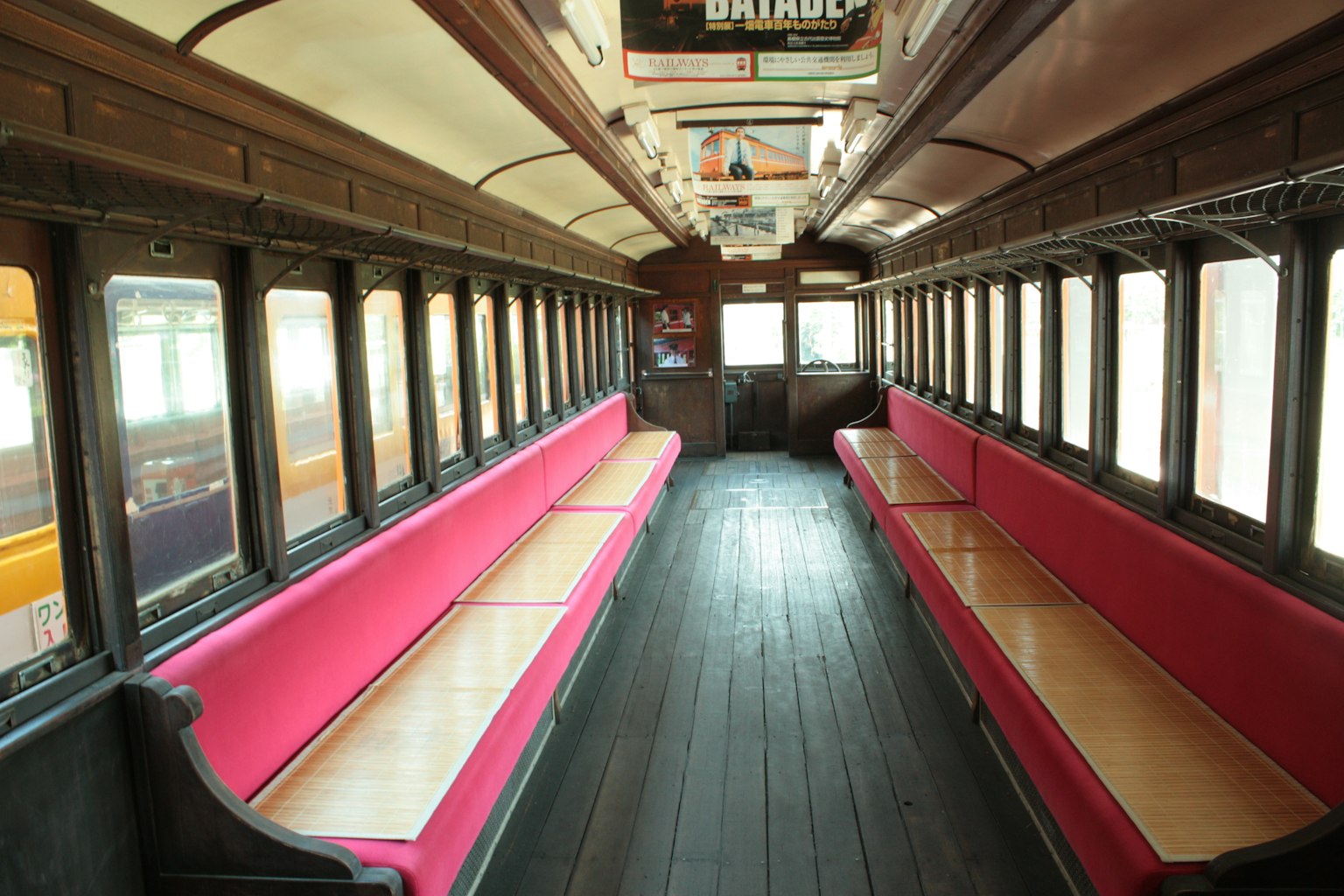 ภายในรถไฟเก่าที่มีม้านั่งสีชมพูและพื้นไม้