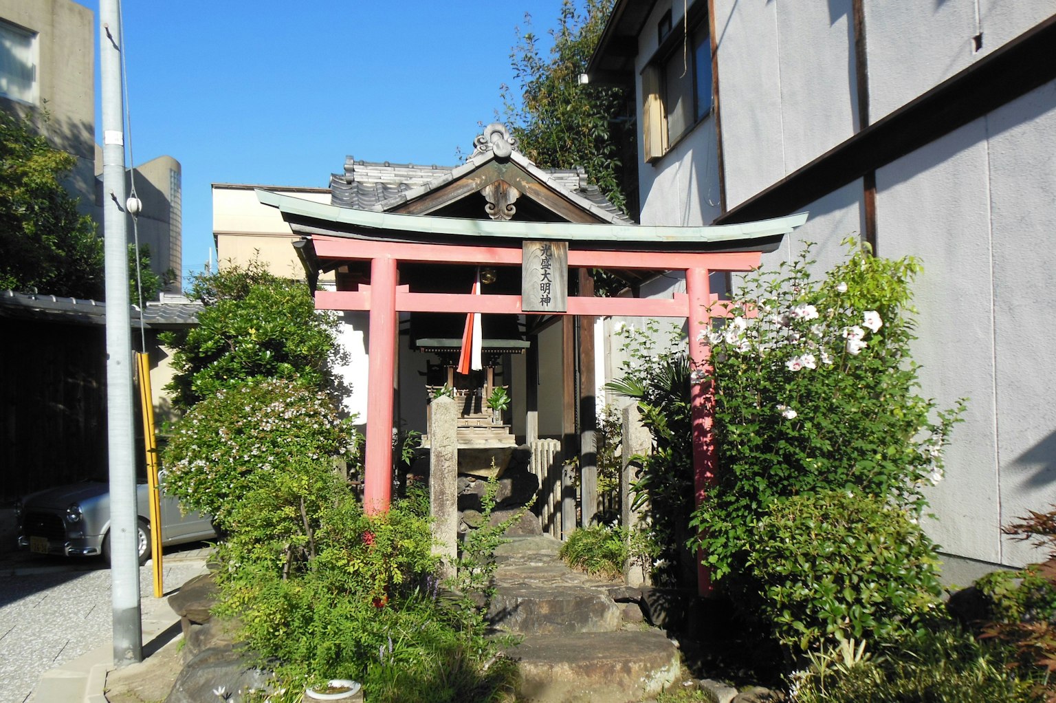 Entrée d'un sanctuaire avec un torii rouge et une végétation luxuriante