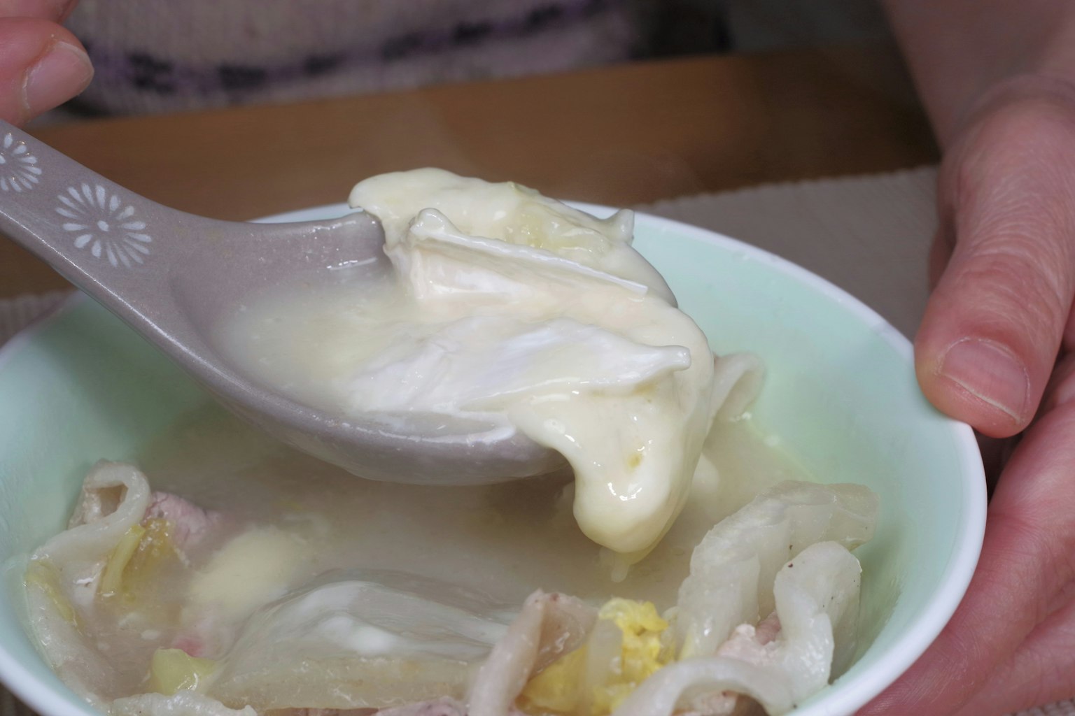 Une cuillère soulevant une soupe crémeuse avec des ingrédients d'un bol