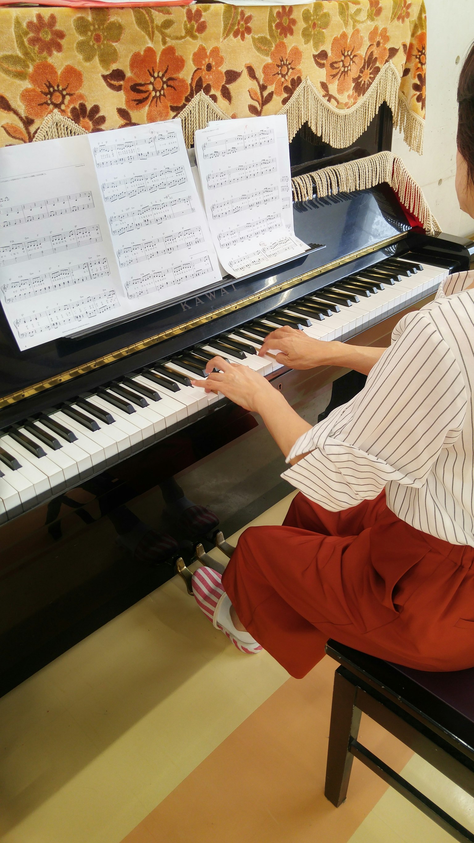 Seorang wanita bermain piano dengan lembaran musik terlihat