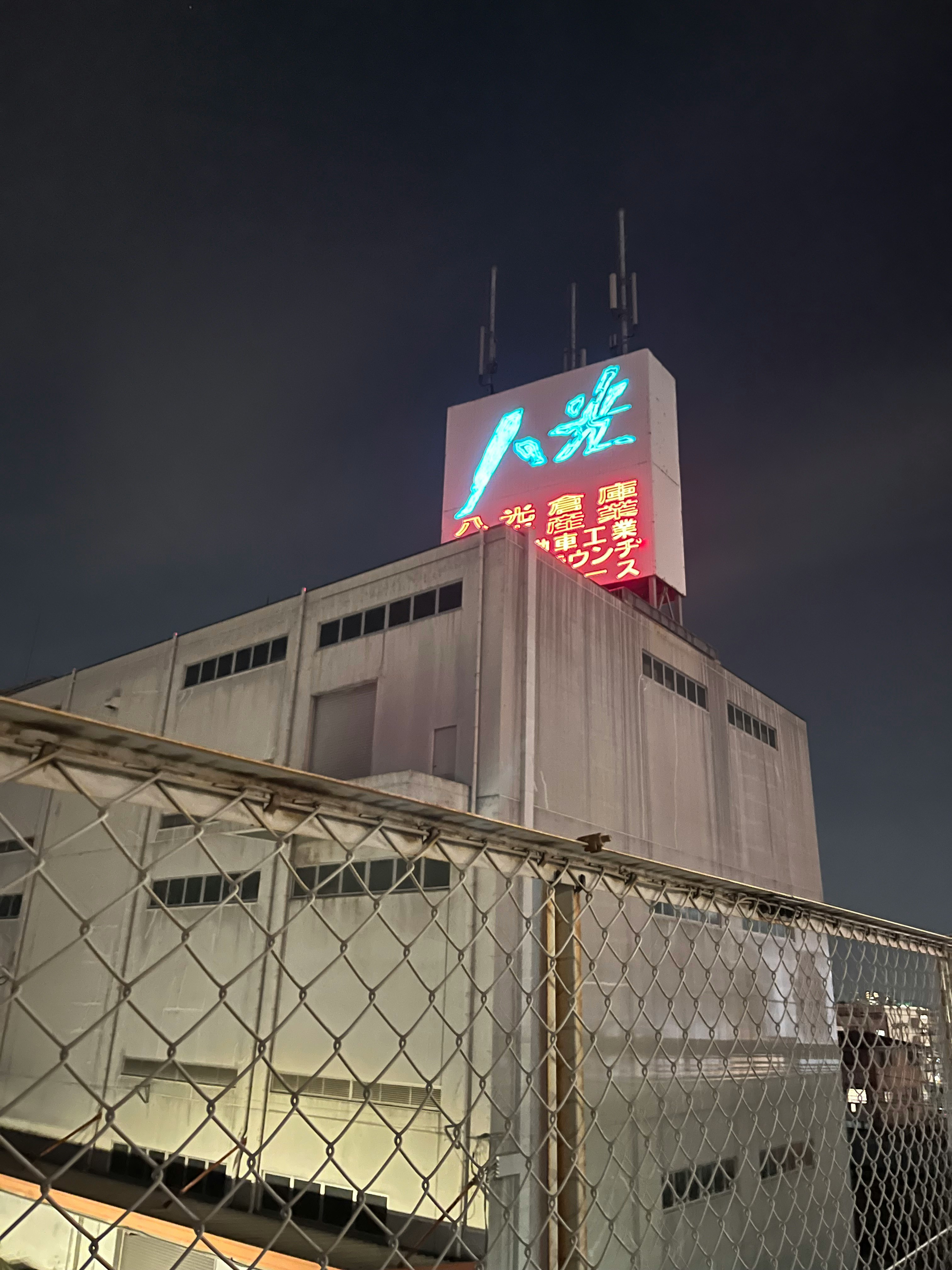 夜の工場建物の上に掲げられたネオン看板