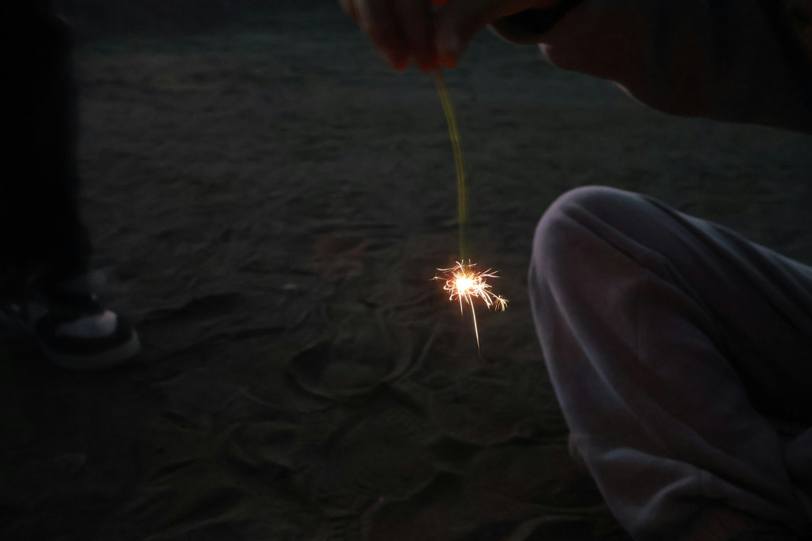 手持ち花火の火花が地面に散る夜の情景
