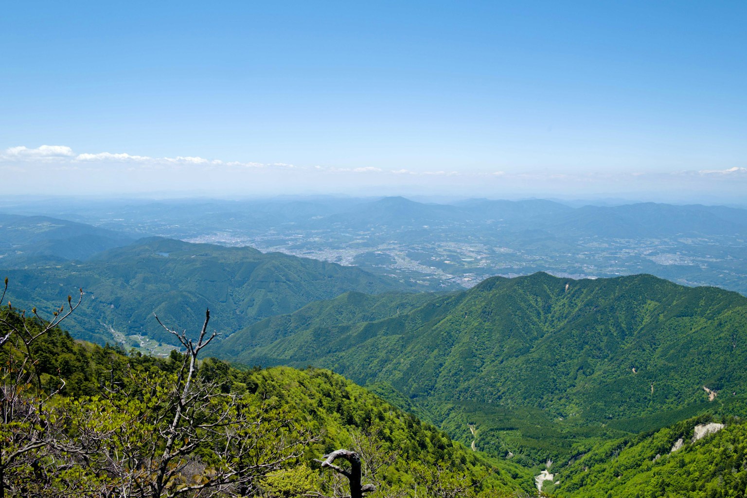 Pemandangan panorama pegunungan hijau di bawah langit biru yang cerah