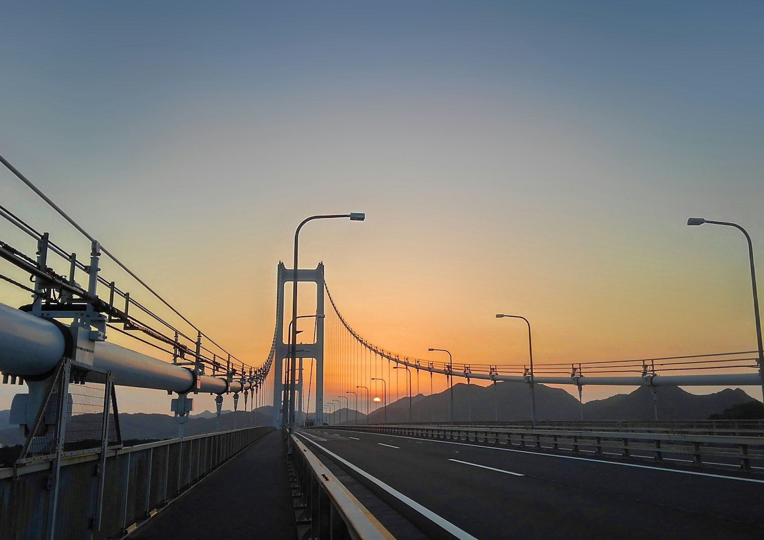 Vue du pont avec un coucher de soleil route surélevée et montagnes visibles