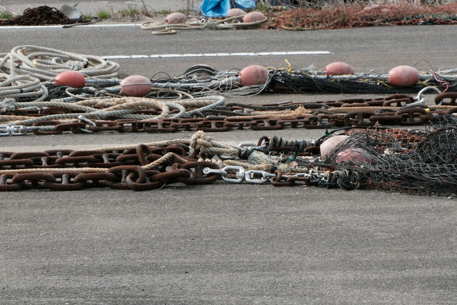 Peralatan memancing termasuk jaring, rantai, dan pelampung terletak di tanah