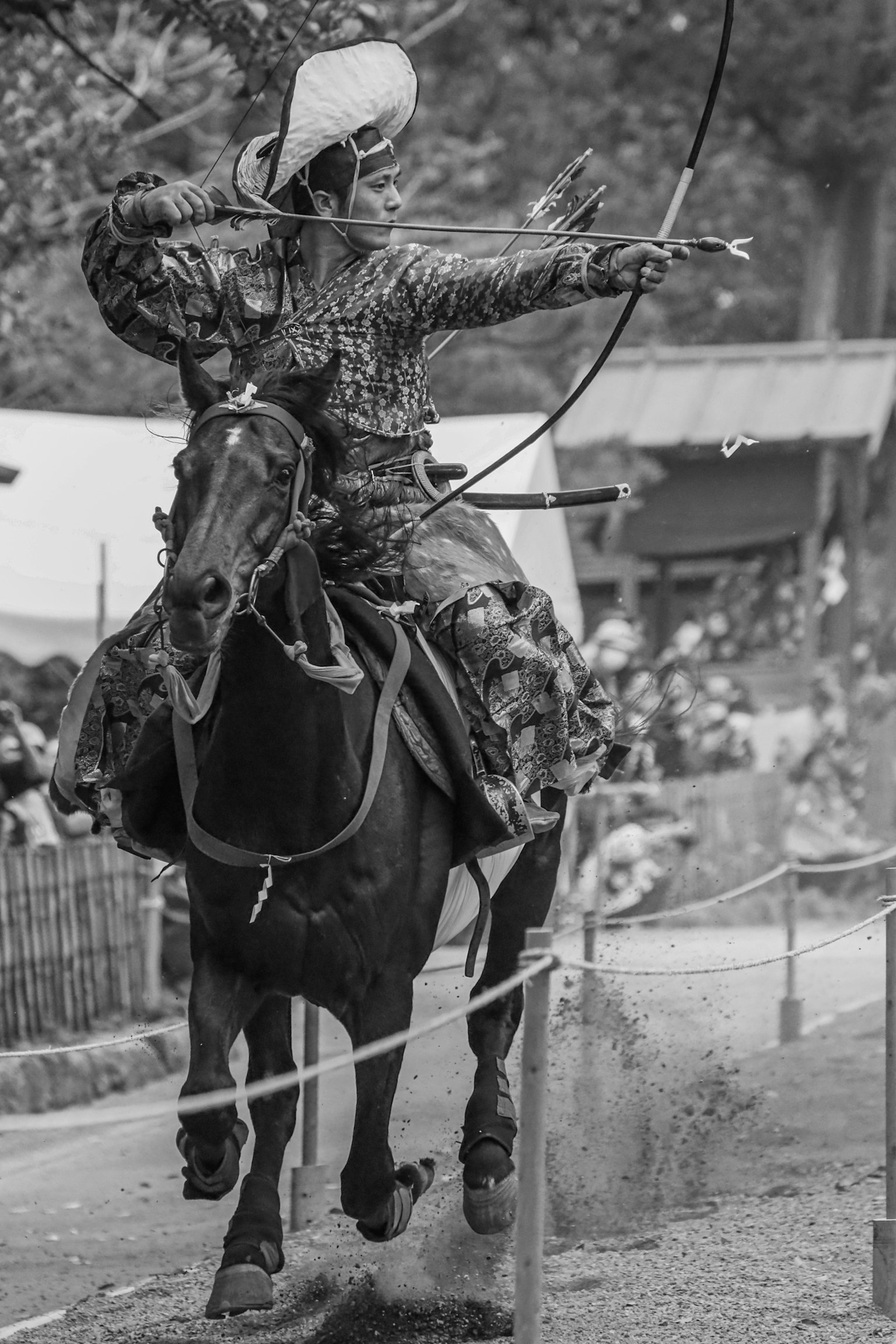 Un cavaliere a cavallo che spara una freccia in una foto in bianco e nero con un'atmosfera festosa vivace sullo sfondo
