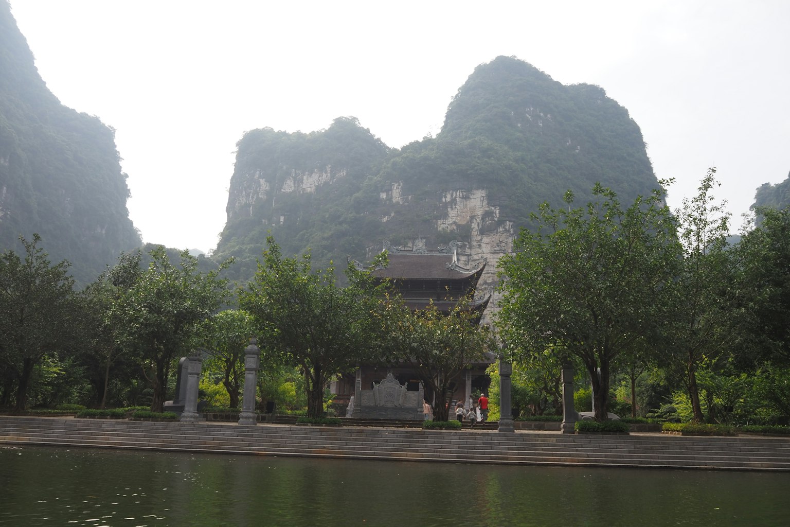 一座古老的寺廟，位於寧靜的湖邊，四周環繞著山脈和茂密的樹木