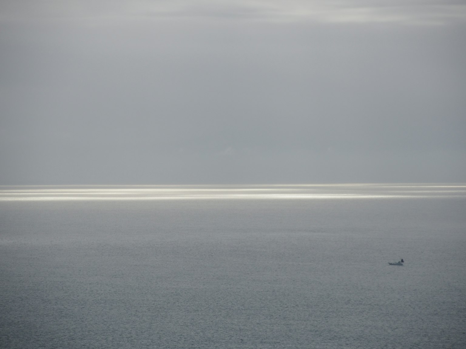 Una vista serena dell'oceano con cielo nuvoloso e una piccola barca in lontananza