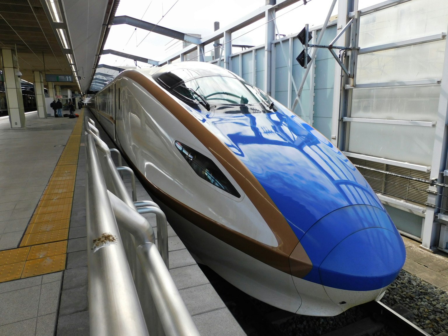 Shinkansen với thân màu xanh và các điểm nhấn màu nâu đỗ tại ga