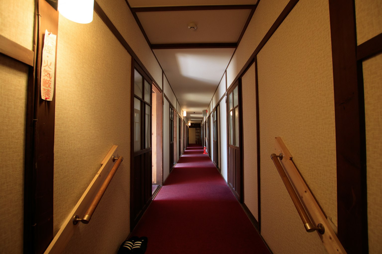 Intérieur d'une auberge japonaise avec un long couloir et un tapis rouge