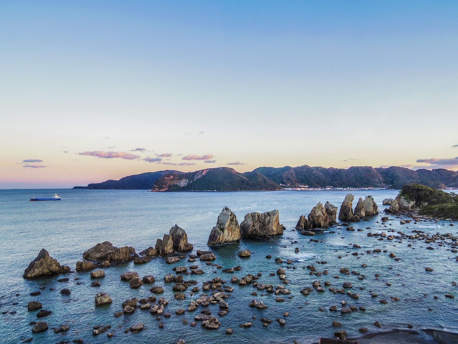 Formazioni rocciose lungo la costa con mare calmo e cielo al tramonto