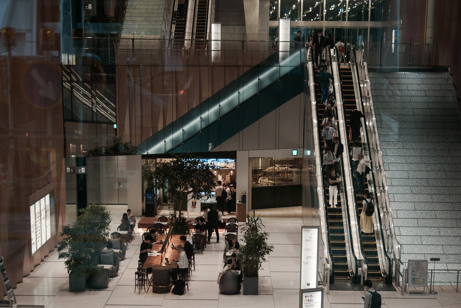 Intérieur d'un bâtiment commercial moderne avec des escalators et un café