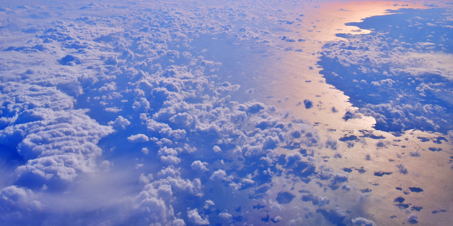 Vista aerea di nuvole e oceano blu che riflette la luce del sole